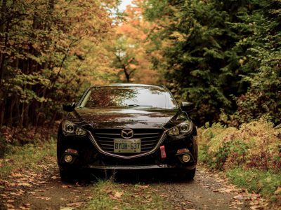 Black Mazda car with Ohio license plates in the woods with reflection on the windshield